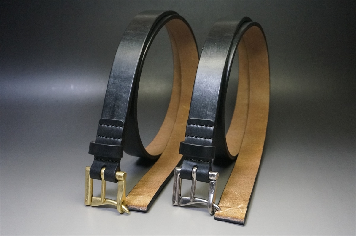 Two leather belts with metal buckles, one gold-tone and one silver-tone, displayed upright on a gray backdrop