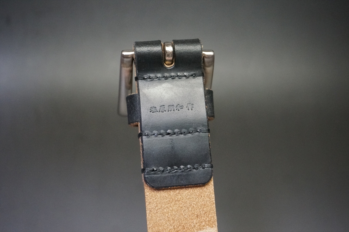 Close-up of a black leather belt loop with a metal buckle and tan suede belt.