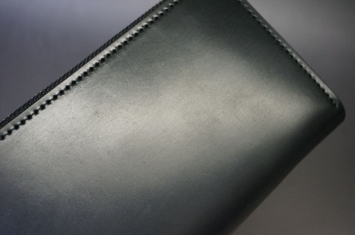 Close-up of a black leather wallet corner with neat topstitching along the edge.