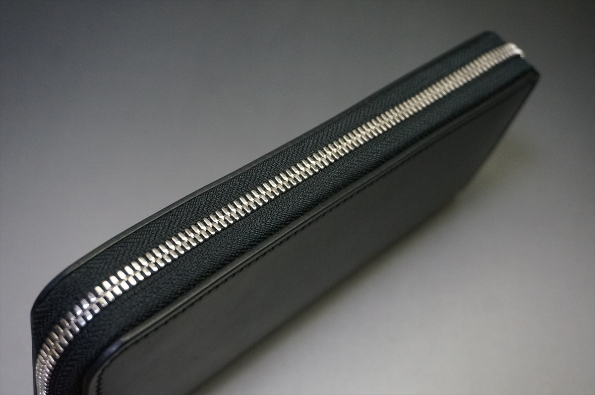 Close-up of a black leather zippered pouch with a silver metal zipper along the edge.