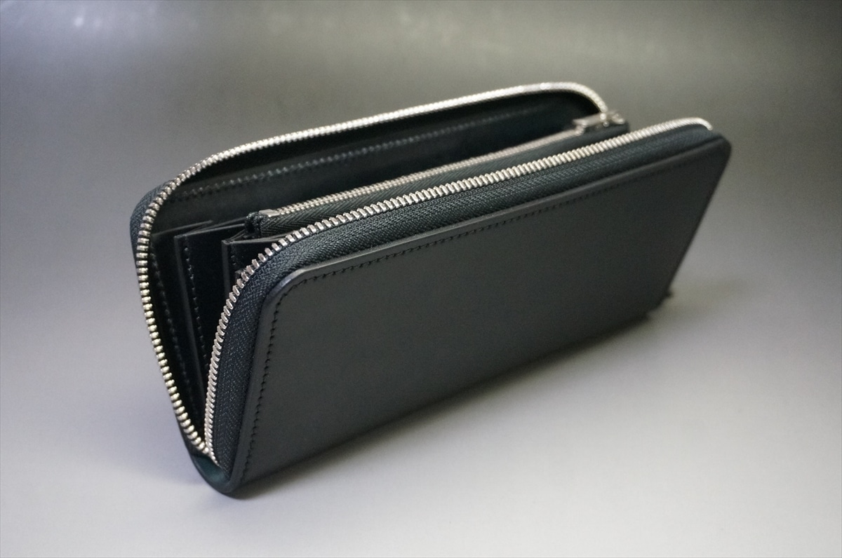 Black leather zip wallet with multiple compartments on a light surface, opened to show card slots and zippers in silver.