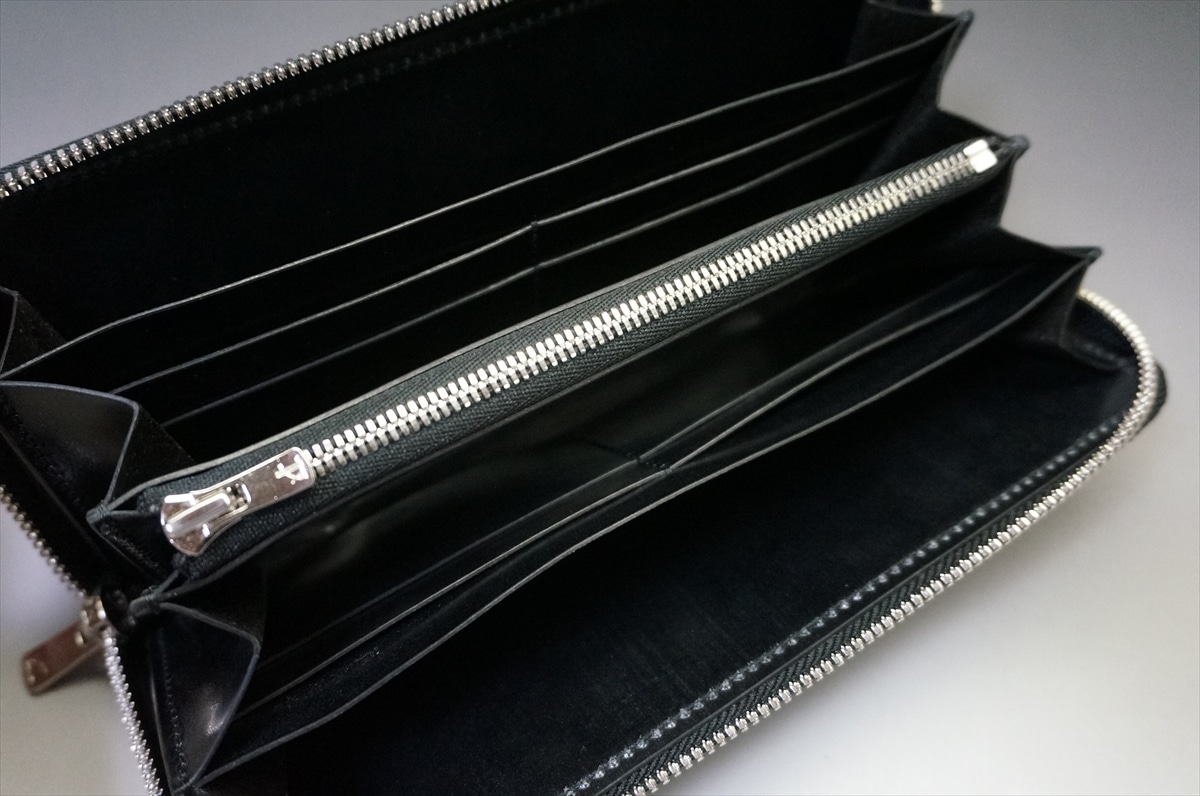 Open black leather wallet showing multiple card slots and a central zip compartment with a silver zipper pull.