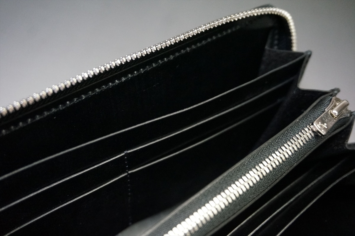 Open black wallet showing multiple card slots and a central zippered pocket for coins or valuables in a sleek interior area.