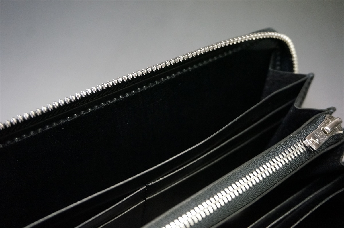 Close-up of a black wallet with a silver zip-around zipper along the edge.