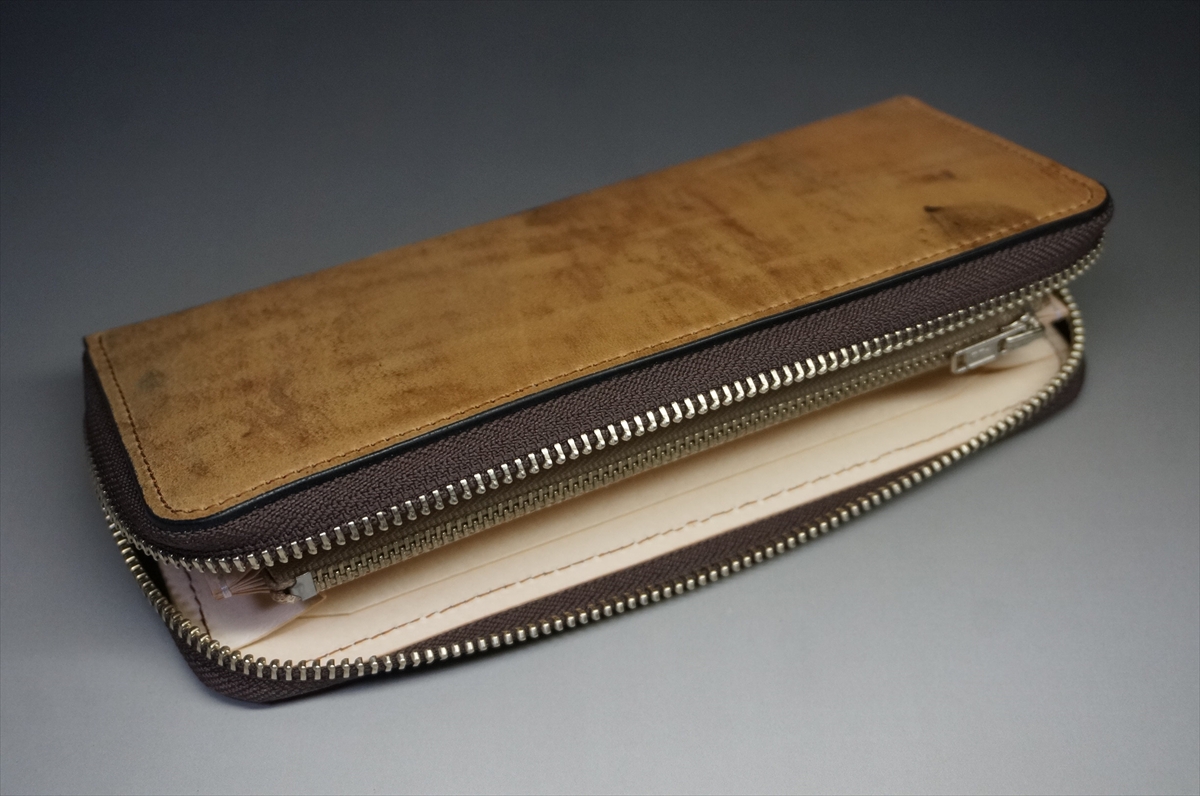 Brown leather zippered wallet opened to reveal beige interior and multiple compartments