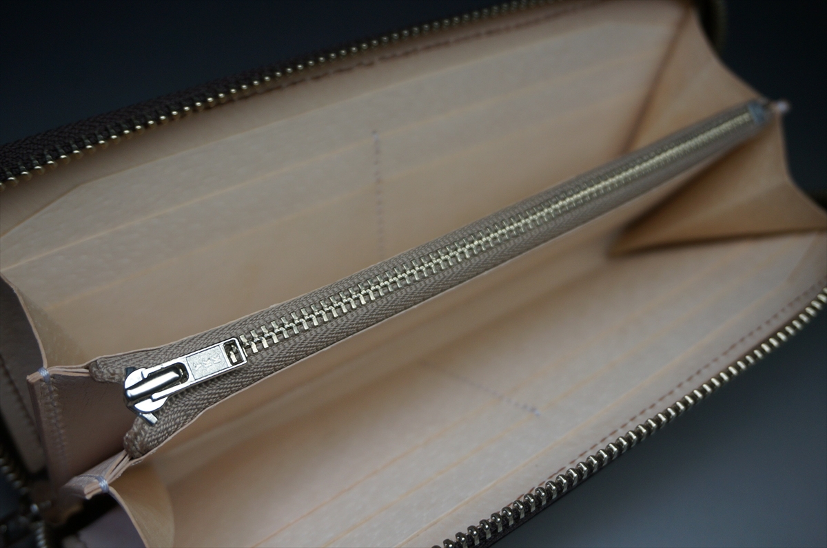 Beige leather wallet interior with a long metal zipper running along the center.