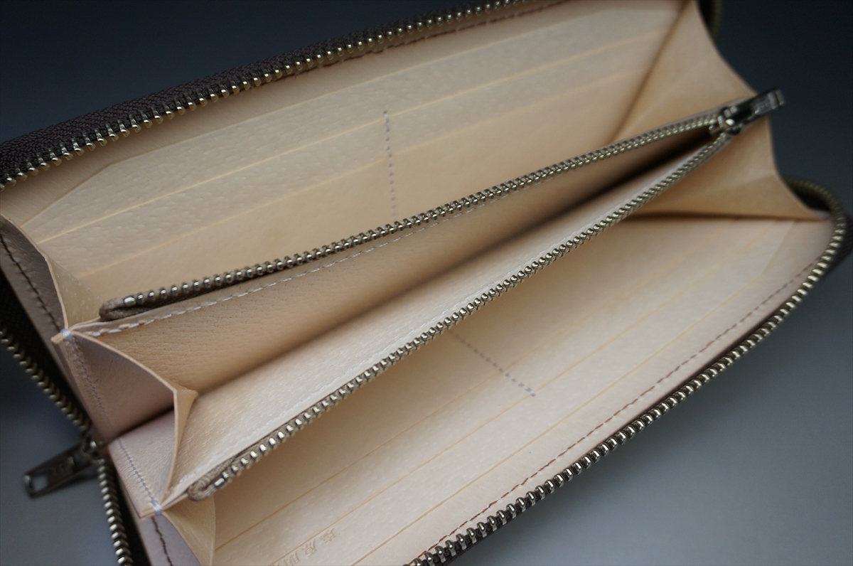 Beige leather zip-around wallet opened to show card slots and a central zip pocket.