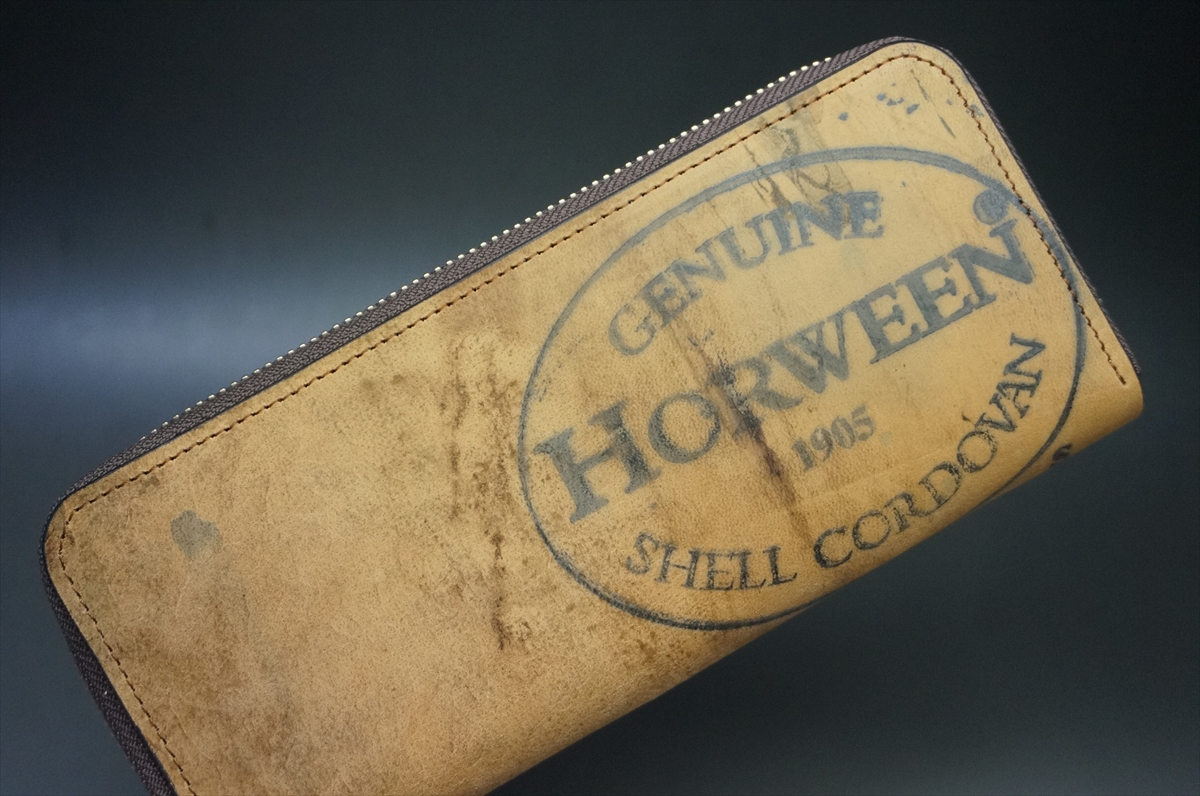 Brown leather zippered wallet with a worn surface and a stamped 'Genuine HORWEEN Shell Cordovan 1995' seal.