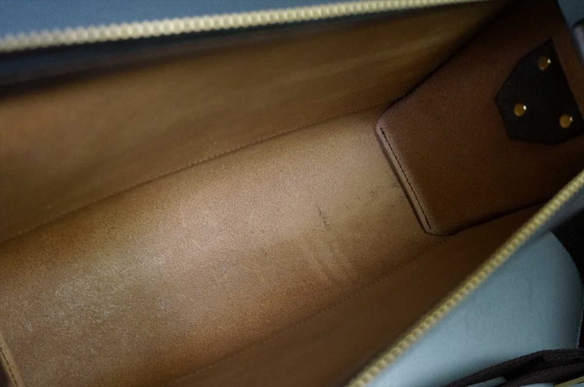 Open brown leather bag interior with a light tan lining and visible zipper edge at the top