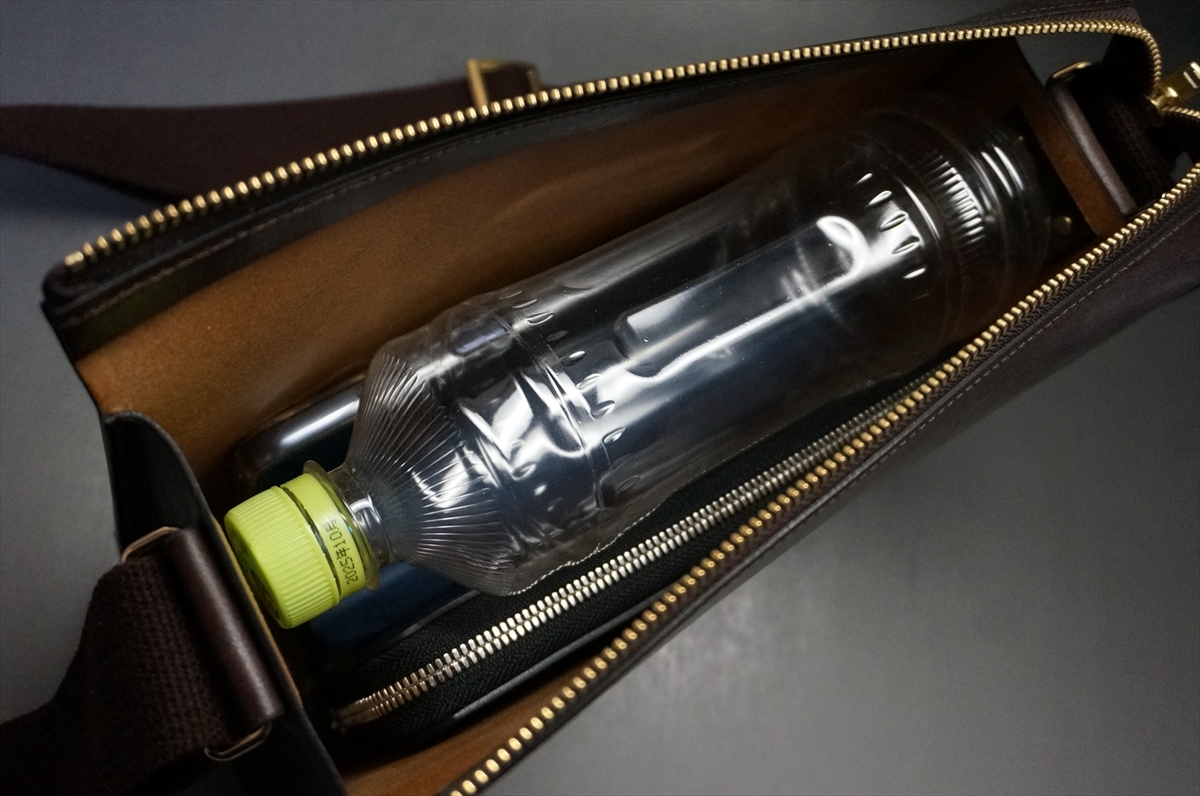 Clear plastic water bottle with a lime-green cap rests inside an open brown zippered bag.