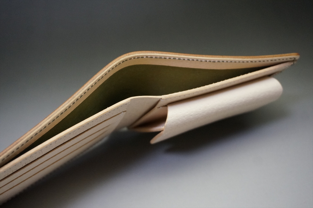 Open beige leather wallet with multiple card slots, showing a green interior and stitched edges.