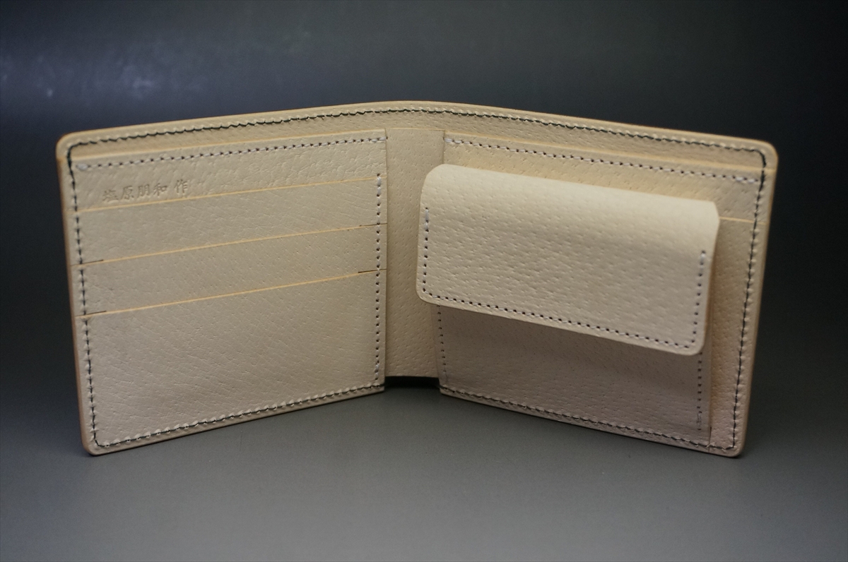 Beige leather wallet opened to reveal card slots on the left and a small pocket pouch on the right.