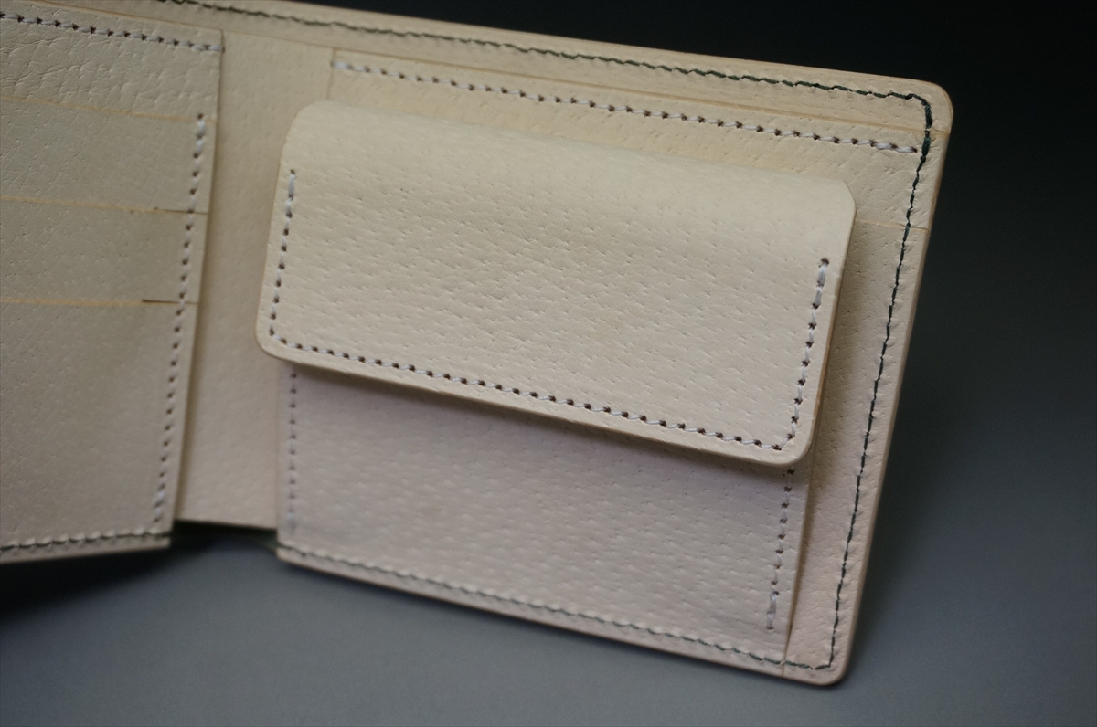 Beige leather wallet open to show compartments and card slots with stitched edges.