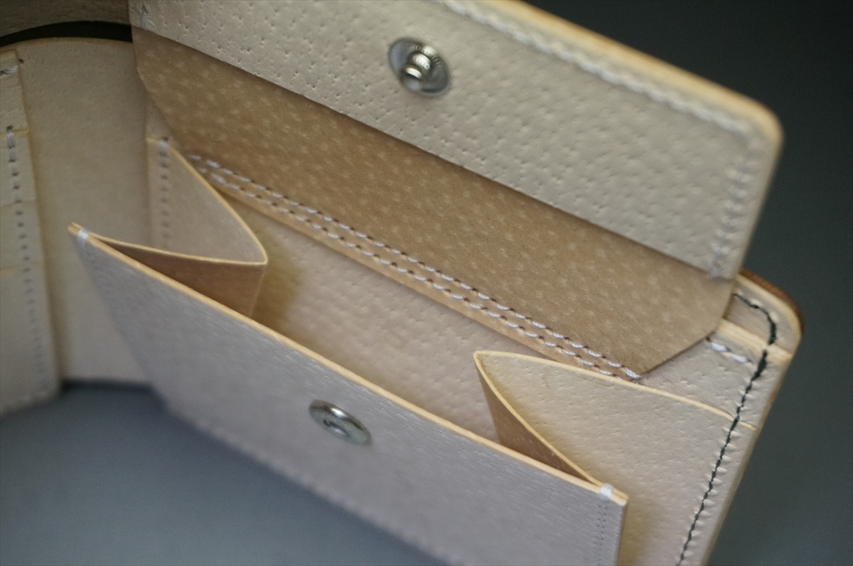 Open beige leather wallet showing card slots and a snap closure.