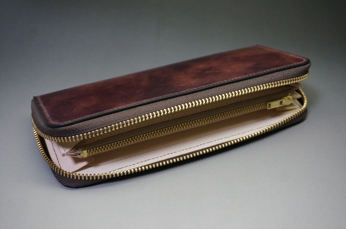 Brown leather zip wallet opened to show multiple compartments and gold zippers; empty interior spaces visible.