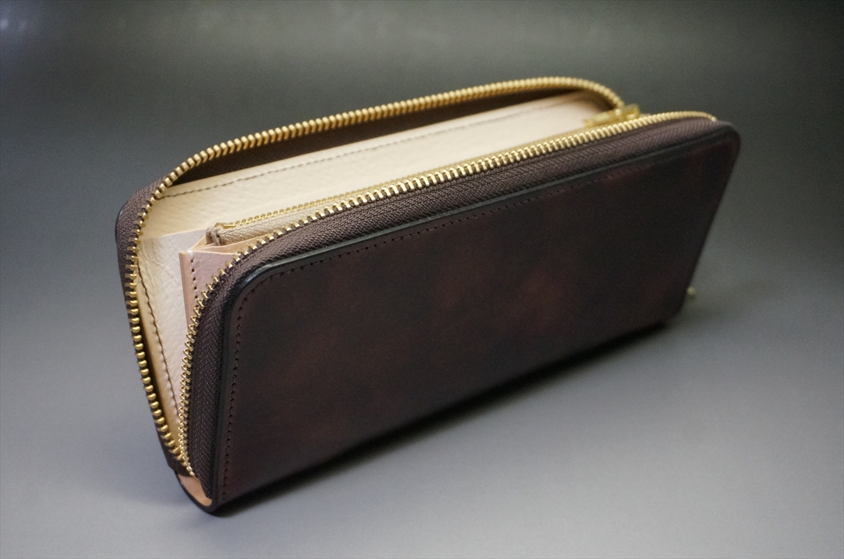 Brown leather zip-around wallet opened to reveal tan interior and card slots, on a gray background.