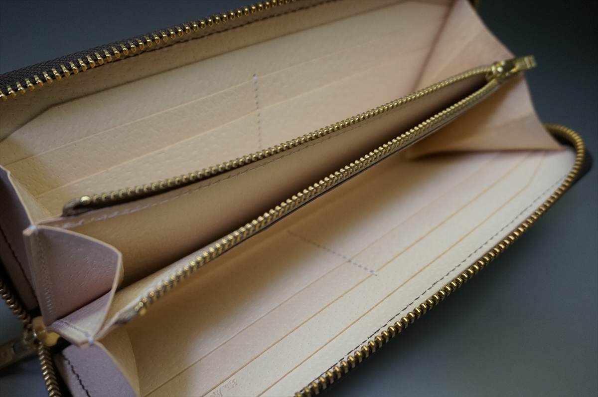 Open beige wallet with multiple card slots and two zip compartments visible, lying flat