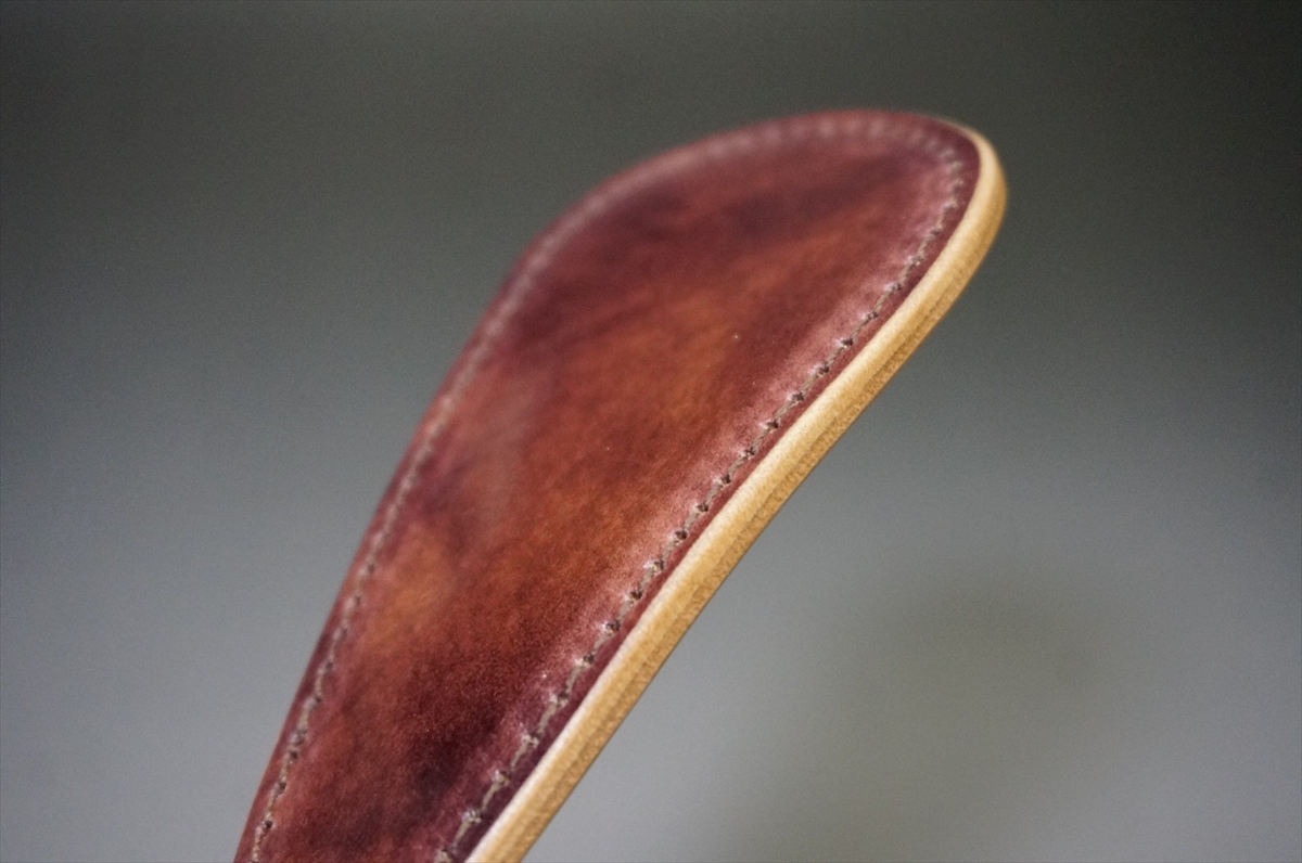 Close-up of a brown leather strap with a light tan edge and visible stitching along the seam.