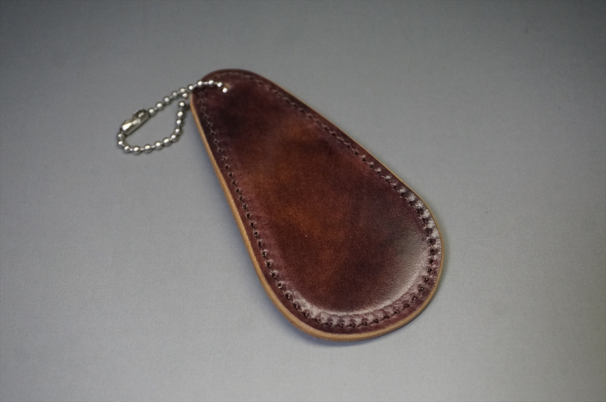 Brown leather teardrop-shaped key fob with a small metal ball chain attached