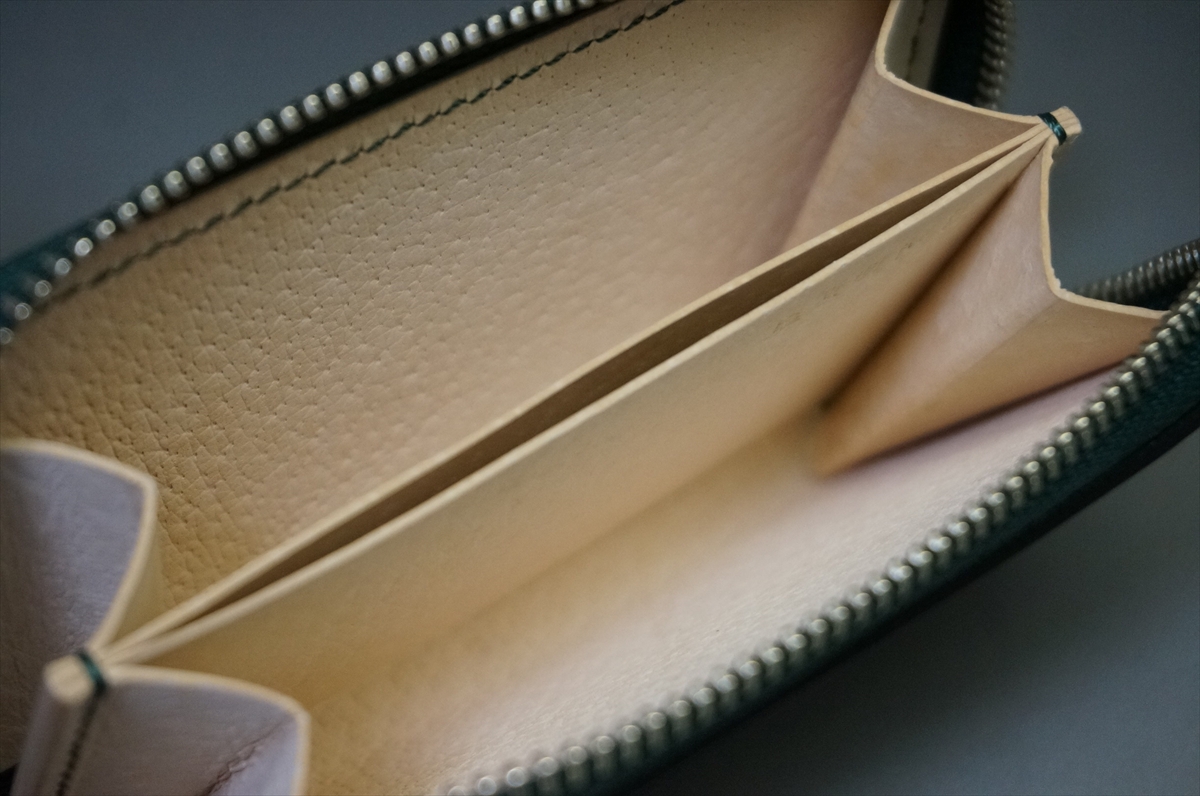 Open beige leather wallet interior with two card slots and a central divider, showing textured lining.