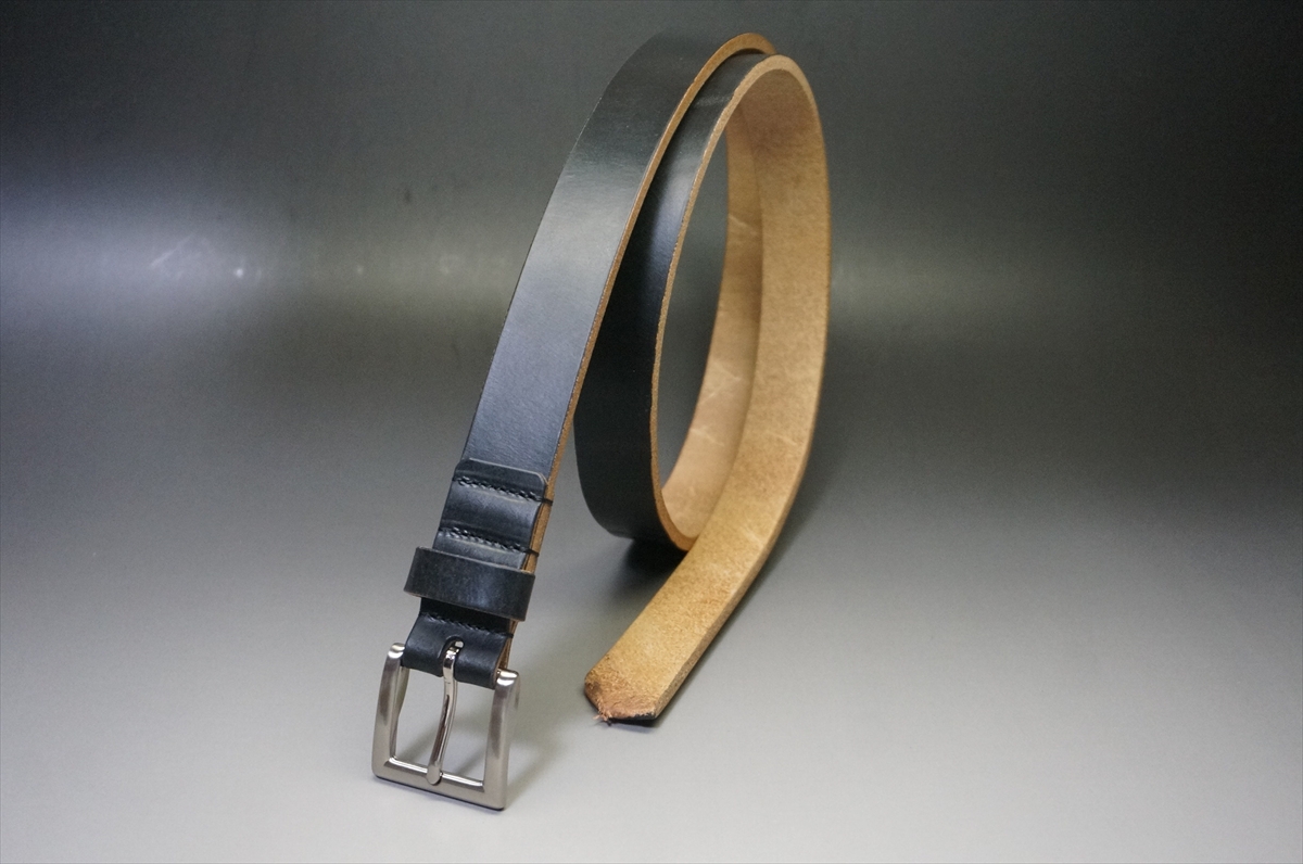 Black leather belt with a silver buckle, laid over a gradient background; the belt is coiled with the tan underside visible at the end.