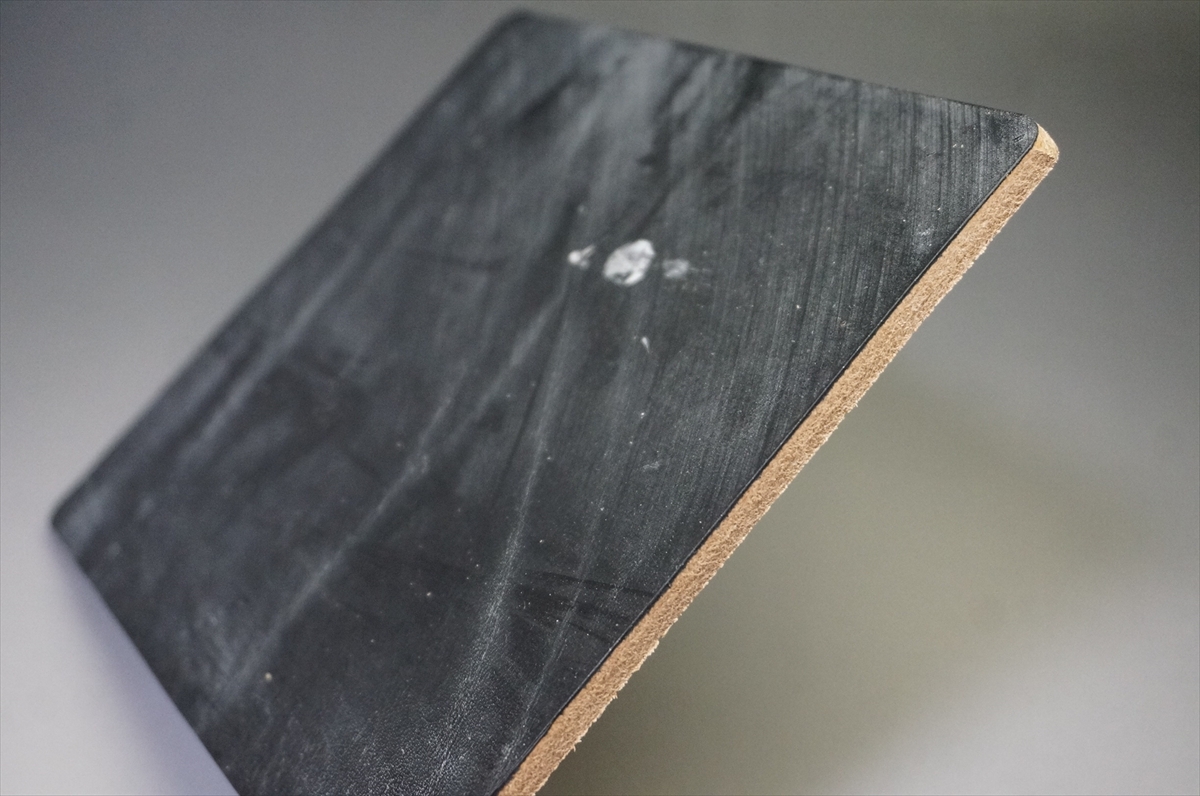 Close-up of a rectangular black cutting board with a natural cork edge.