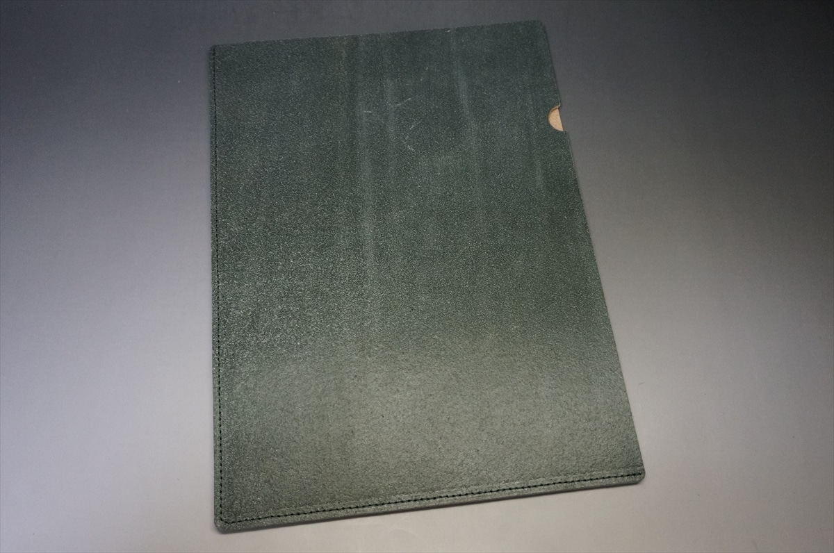 Dark green, textured notebook cover with a small rounded notch on the right edge, shown on a gray gradient background.