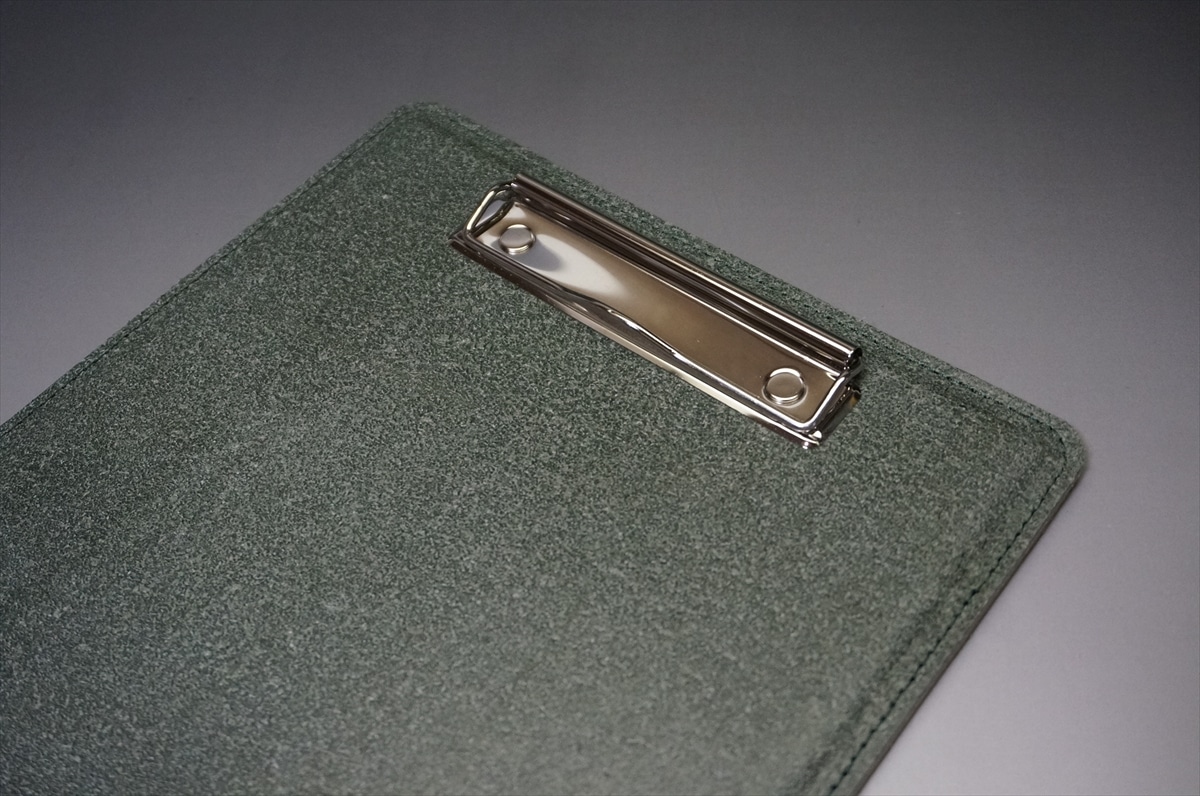 Green textured clipboard with a shiny silver metal clip along the top edge