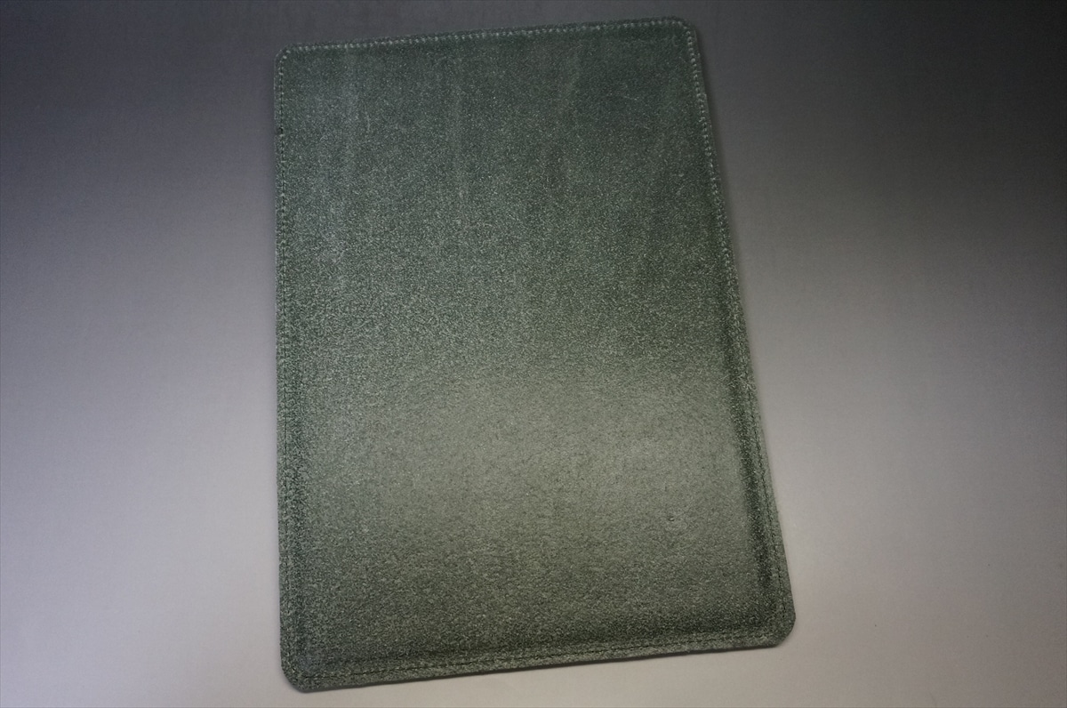 Dark green textured notebook or journal cover with rounded corners on a light surface—diagonal orientation