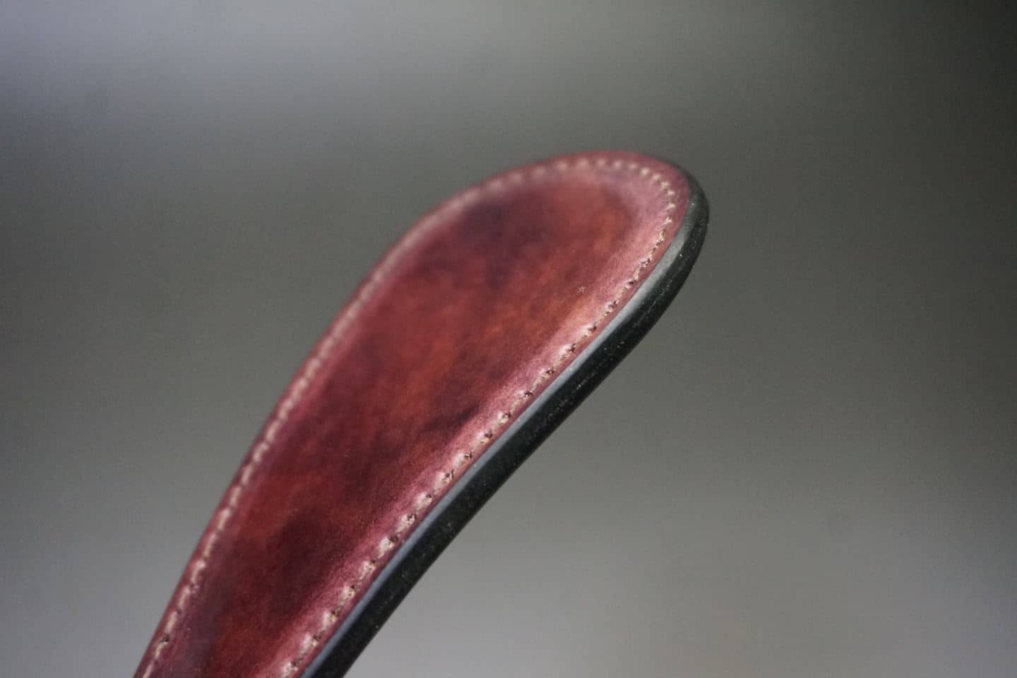 Close-up of a reddish-brown leather strap with visible white stitching and a dark edge.